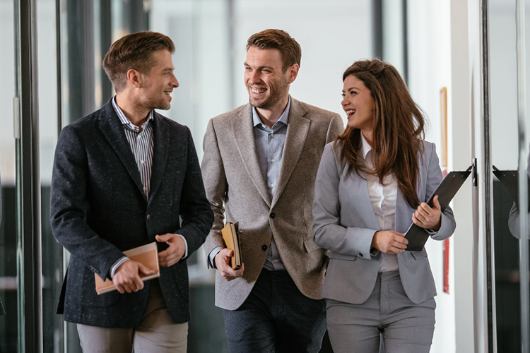 Groupe de collaborateurs rigolant ensemble dans le couloir d'une entreprise