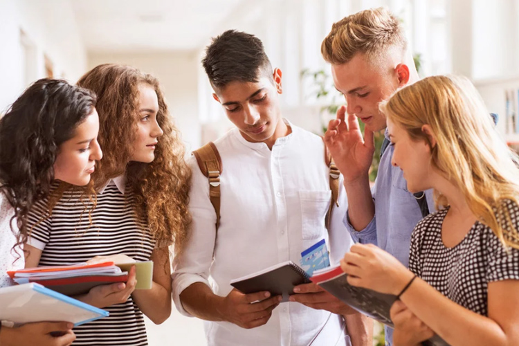 Groupe d'étudiants discutant ensemble en partageant des notes dans un couloir universitaire